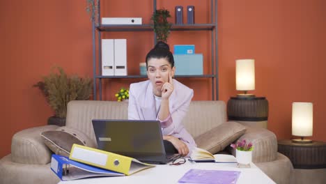Home-office-worker-young-woman-thinking-looking-at-camera.
